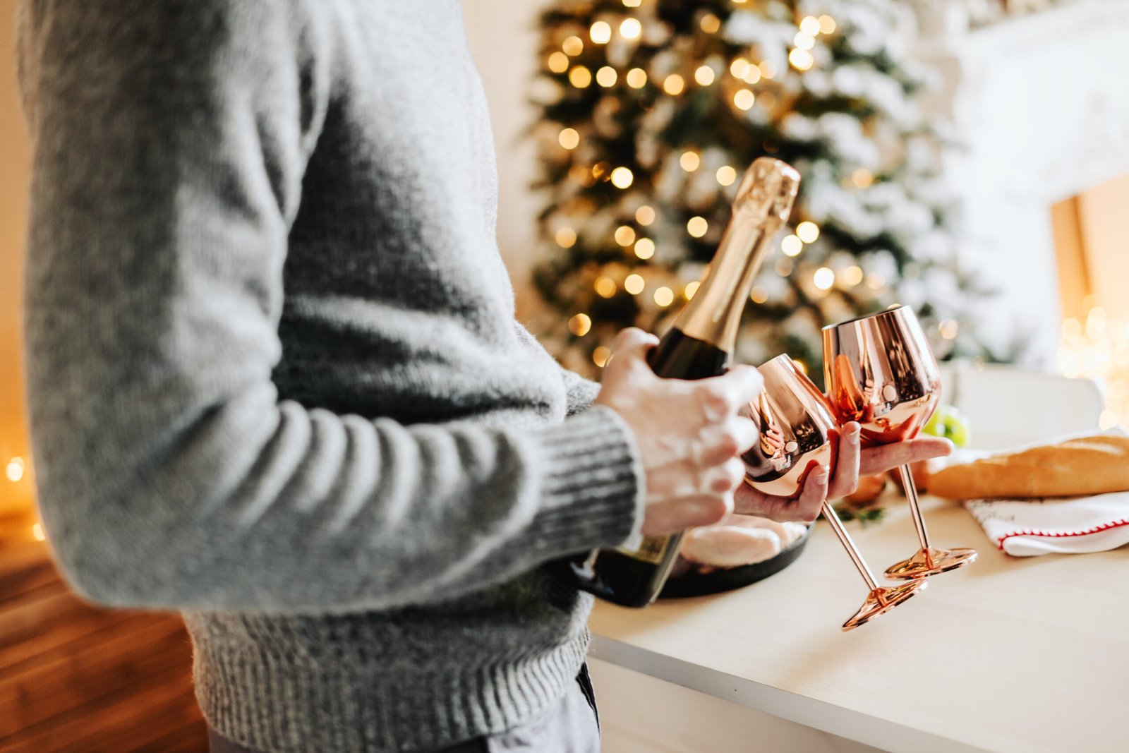 Man holding wineglasses and bottle of champaigne ready for celebrating New Year Party or Christmas at home.