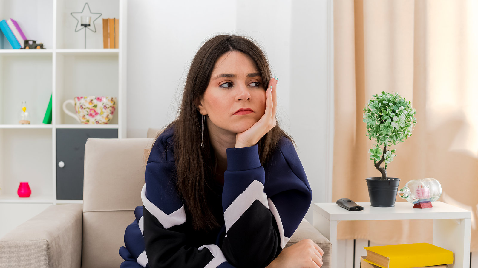 sad-young-pretty-caucasian-girl-sitting-armchair-designed-living-room-looking-side-putting-hand-chin