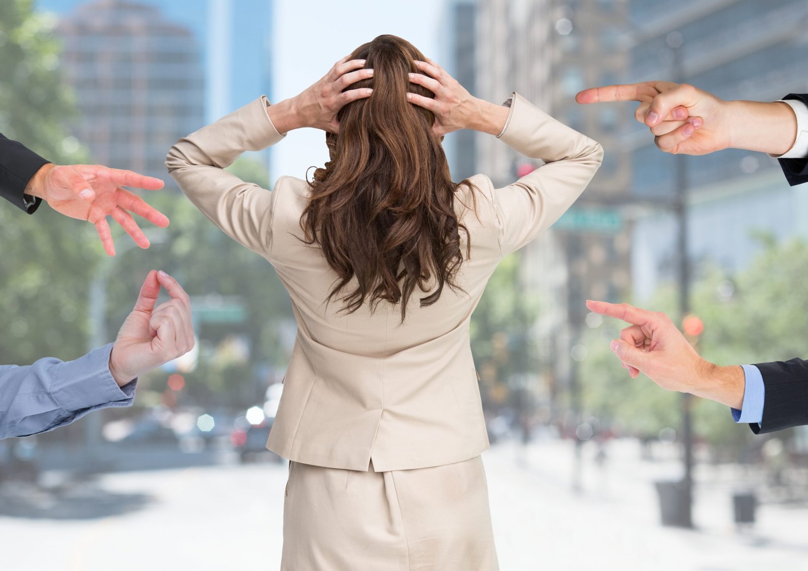 Digital composition of hands blaming a stressed woman against city buildings in background